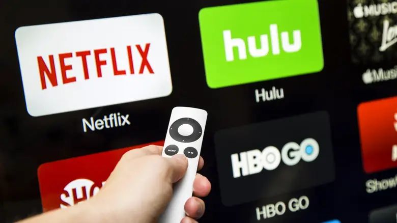 Menggunakan teknologi dengan bijak Seseorang menggunakan aplikasi layanan streaming di ponselnya